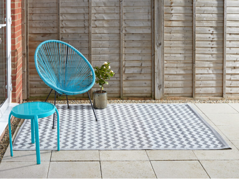 A white and grey outdoor rug with a zig zag pattern