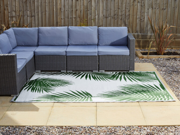 A white rug with green palm leaves used to decorate a garden