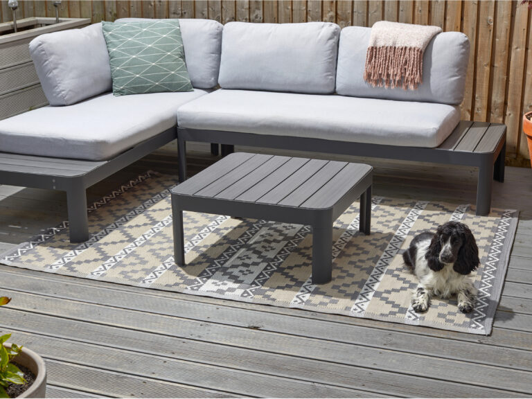 A grey, white and beige patterned outdoor rug on a patio